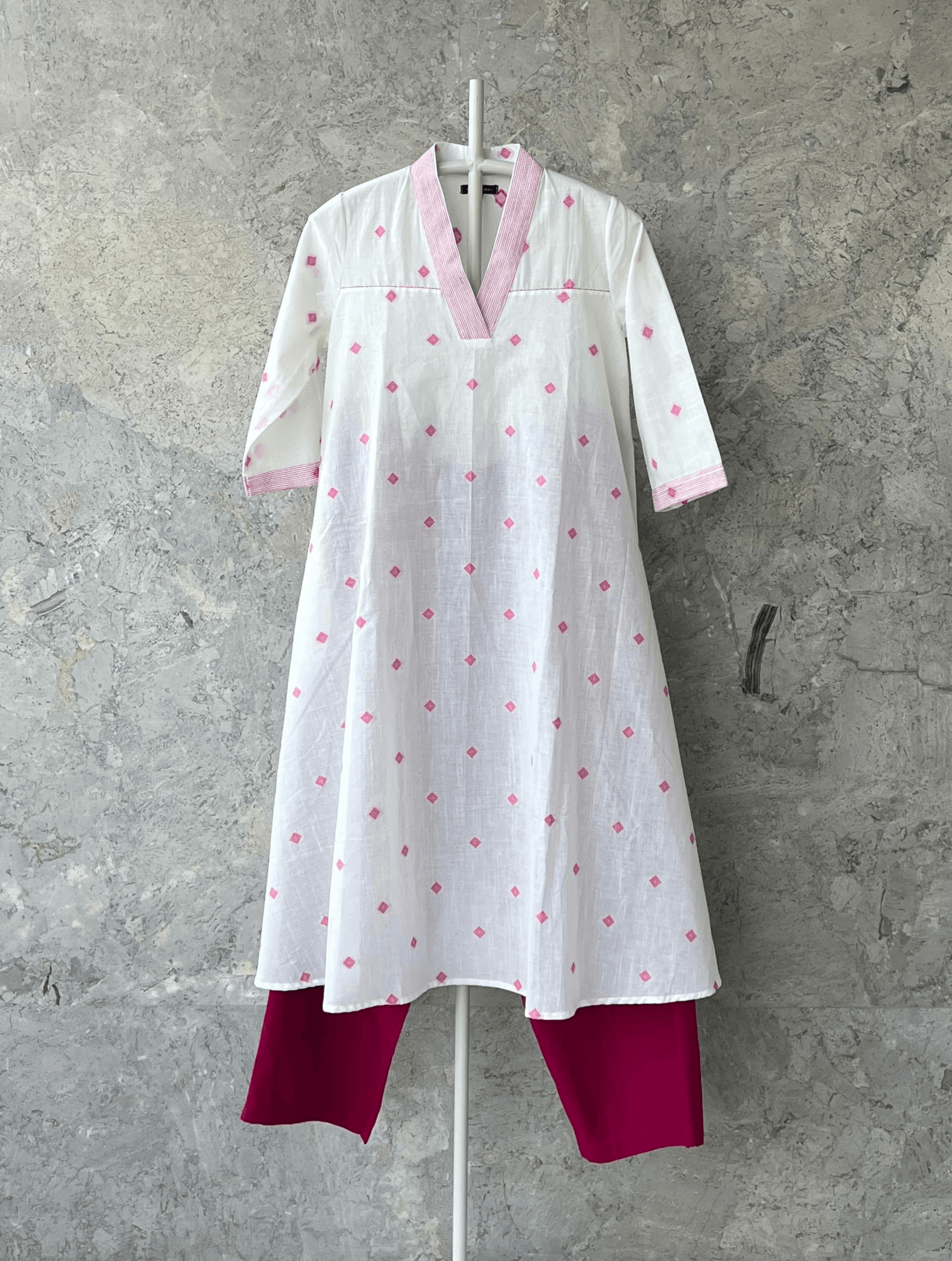 White fit and flare cotton kurta with pink butti, V-neck, and handcrafted detailing by Indian designer Sonal Kabra – summer collection.