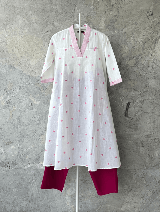 White fit and flare cotton kurta with pink butti, V-neck, and handcrafted detailing by Indian designer Sonal Kabra – summer collection.